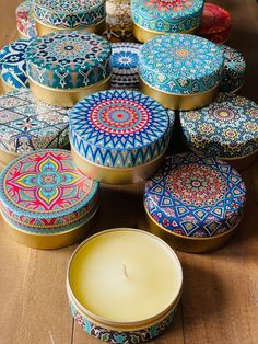 a candle sitting on top of a wooden table next to some tins filled with candles