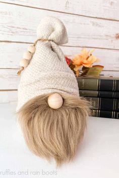 a white knitted hat with long blonde hair on top of some books and flowers