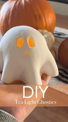 a person holding a fake ghost in front of pumpkins with text overlay that reads diy tea light ghosties