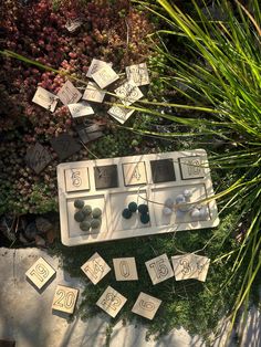 an arrangement of numbers and magnets on display in a garden with green plants around them