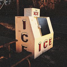 an ice cream stand sitting on the side of a road at night with trees in the background