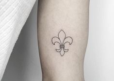 a small black and white fleur de lis tattoo on the arm