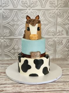 a three tiered cake decorated with a cow and horse head on top of it