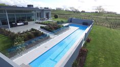 an aerial view of a house with a swimming pool in the foreground and green grass on the other side