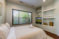 a bedroom with a bed, shelves and a tv in the corner next to it