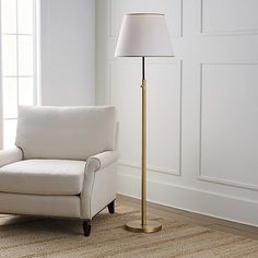 a living room with a white chair and a lamp on the floor next to it