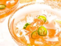 a bowl filled with soup and vegetables on top of a white tablecloth next to two glasses