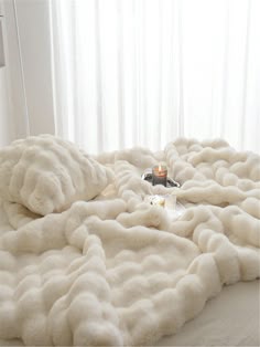 a bed with a white comforter and two candles on the end table next to it