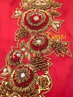 red and gold embroidered fabric with large flowers on the bottom, surrounded by small jewels