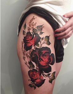 a woman's thigh with roses and leaves tattoo on the side of her leg