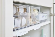 two clear bins filled with different items on top of a white shelf in a kitchen