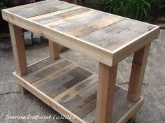 a wooden table sitting on top of a cement ground next to a potted plant