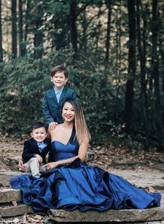 a woman in a blue dress poses for a photo with her two boys on some steps