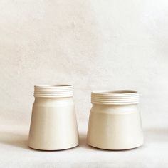 two white jars sitting side by side on a table