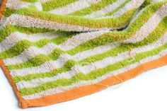 an orange and green striped towel laying on top of a white surface