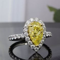 a fancy yellow diamond ring with white diamonds on the sides and an oval shaped center