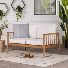 a white couch sitting on top of a rug next to a potted plant