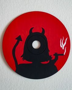 a red and black circular sign with a devil holding a burning matchstick in it's hand