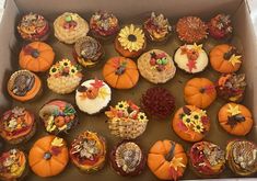 a box filled with lots of cupcakes covered in frosting and decorated pumpkins