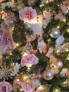 a christmas tree decorated with ornaments and pink roses on it's branches is seen in this image