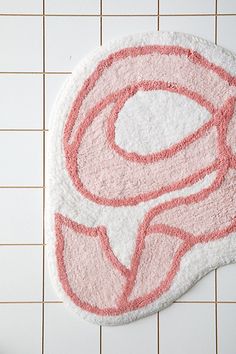 a bathroom rug with the letter c on it in pink and white, next to a toilet paper roll