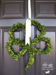 a wreath hanging on the front door of a house that is decorated with greenery