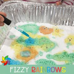 a child is painting with colored water in a tin foil pan and black marker on it