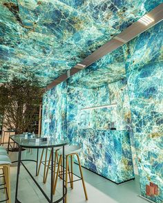 an artisticly designed restaurant with marbled walls and tables in the foreground, surrounded by stools