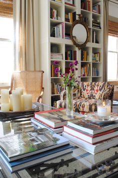 a living room filled with lots of furniture and books on top of a glass table