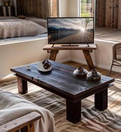 a tv sitting on top of a wooden table in a living room next to a bed