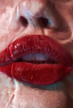 a woman's lips are covered with water droplets and red lipstick is reflected in the mirror