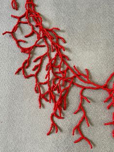 a red piece of string art on a white surface