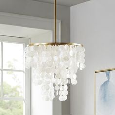 a chandelier hanging from the ceiling in a room with white walls and windows