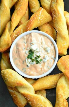 breadsticks arranged around a bowl with dip in it