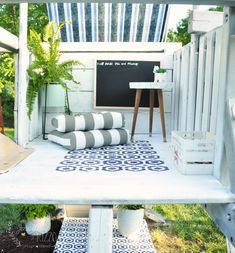 an outdoor area with a table, couch and potted plants on it's side