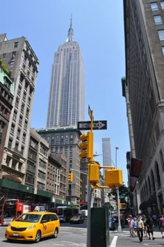 a yellow taxi cab is stopped at an intersection in front of the empire state building