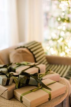 wrapped presents sitting on a table in front of a christmas tree