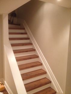 there is a stair case in the corner of this room with no carpet on the floor