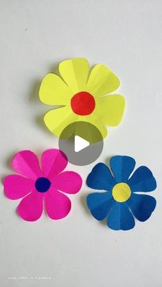 three paper flowers sitting on top of a white surface with one flower cut in half