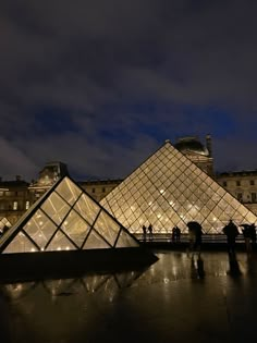 people standing in front of the pyramid at night