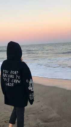 a person walking on the beach with a hoodie saying you don't belong to this crew inside