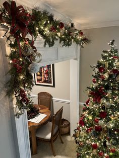 a christmas tree is decorated with red and green ornaments in the corner of a dining room