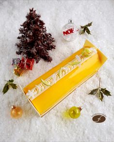 a yellow box sitting on top of snow covered ground next to christmas trees and ornaments