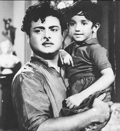 an old black and white photo of a man holding a young boy in his arms