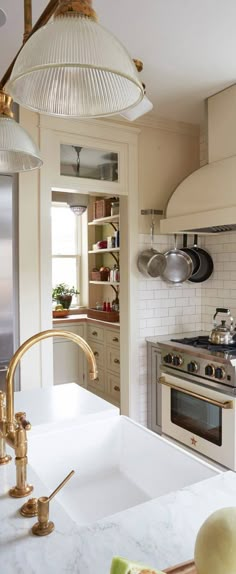 a kitchen with an oven, sink and counter tops in white marble or gold metal