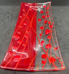 two red and clear plates sitting on top of a gray surface with drops of water