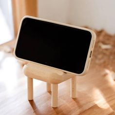 a small wooden table with a cell phone on it's legs, sitting on top of a hard wood floor