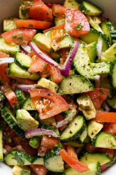 a white bowl filled with cucumber, tomato and onion salad