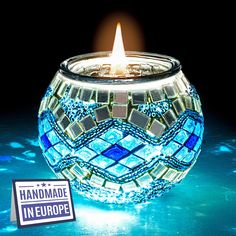 a lit candle sitting on top of a blue table next to a sticker that says handmade europe