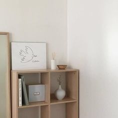 a shelf with books, vase and mirror on it